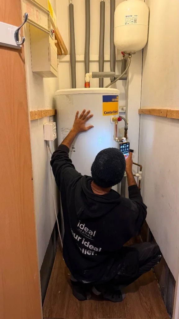 Heating engineer inspecting a hot water cylinder in a utility cupboard