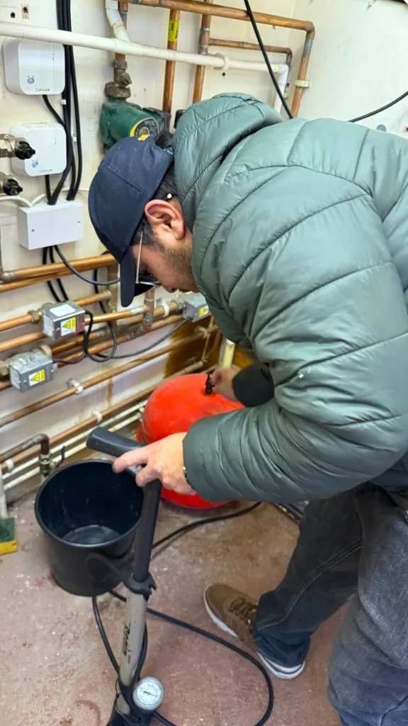 Engineer pressurising a red expansion vessel on a domestic heating system